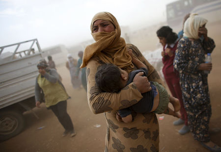 © Reuters. A Kurdish Syrian refugee waits for transport during a sand storm on the Turkish-Syrian border near the southeastern town of Suruc