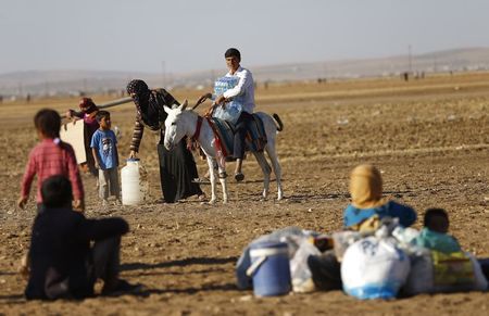 © Reuters. Refugiados curdos da Síria levam pertences após atravessar fronteira Turquia-Síria para fugir do Estado Islâmico