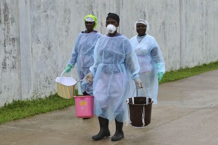 © Reuters. Health workers carry buckets of disinfectant at the newly-constructed Island Clinic and Ebola treatment center in Monrovia