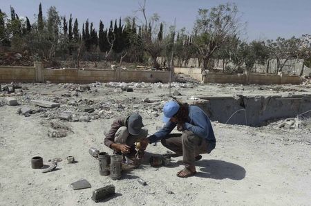 © Reuters. En la imagen, civiles examinan los restos que dejó  un ataque de Estados Unidos contra una base del Frente Al-Nusra en Siria.