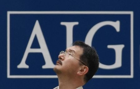 © Reuters. A man stands in front of an AIG logo in Tokyo