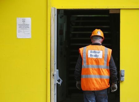© Reuters. A Balfour Beatty construction worker walks onto a site in London