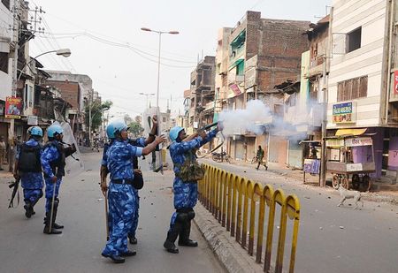 © Reuters. A RAF member fires a tear gas shell to disperse a mob after clashes in Vadodara