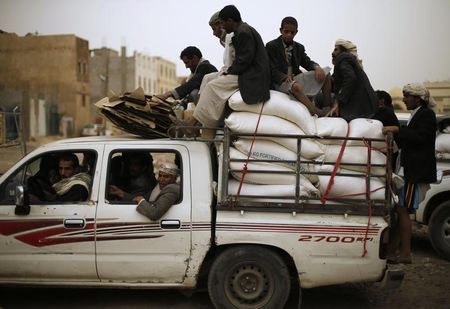 © Reuters. People ride atop a pick-up vehicle after they received foodstuff assistance from a World Food Programme distribution center for people displaced by armed conflicts in northern Yemen, in Sanaa