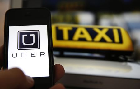 © Reuters. An illustration picture shows the logo of car-sharing service app Uber on a smartphone next to the picture of an official German taxi sign