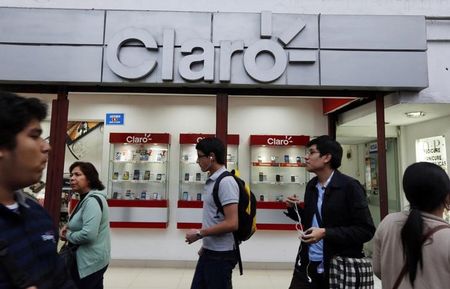 © Reuters. People walk outside a mobile phone store of network company Claro in Lima