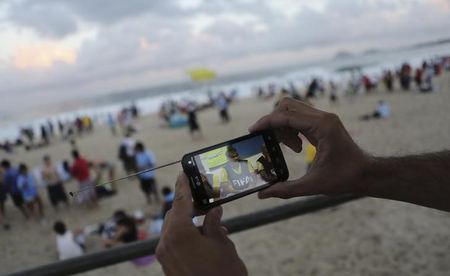 © Reuters. Torcedor assiste a uma partida da Copa do Mundo de 2014 pelo celular, em Copacabana, no Rio de Janeiro