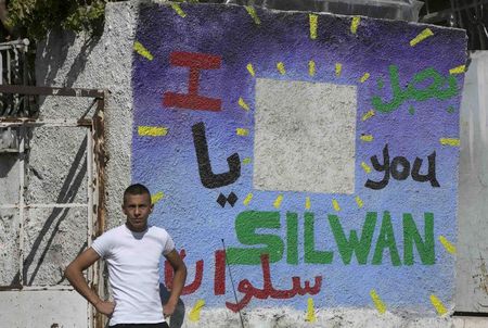 © Reuters. A Palestinian youth stands outside a house which Jewish settlers moved into, in Silwan, Jerusalem