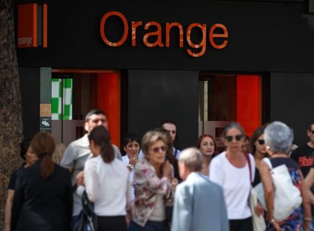 © Reuters. People cross a street in front of an Orange shop in Madrid