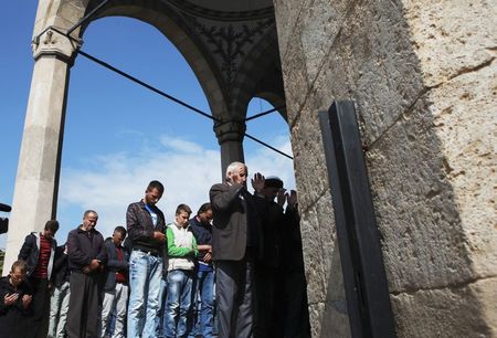 © Reuters. Kosovar Albanians perform Friday prayers at the entrance of a mosque in Pristina