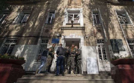 © Reuters. Pro-Russian rebels stand at the entrance of a school after it was hit by shelling in Donetsk