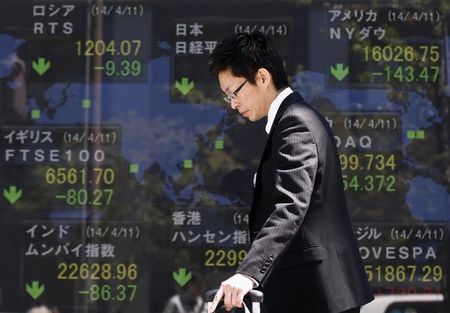 © Reuters. A man walks past at an electronic board displaying various countries' share prices outside a brokerage in Tokyo