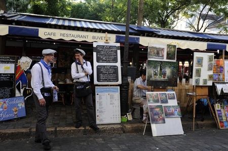 © Reuters. Waiters stand outside a cafe at the Place du Tertre square in the former village of Montmartre near the Sacre Coeur Basilica in Paris