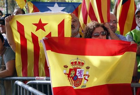 © Reuters. Una sostenitrice dell'unità della Spagna sventola una bandiera spagnola davanti a un sostenitore dell'indipendenza catalana