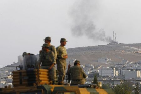 © Reuters. Soldados turcos em veículo blindado, com a cidade síria de Kobani ao fundo, perto da fronteira Síria-Turquia