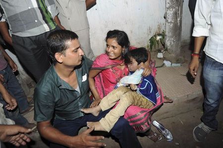 © Reuters. A woman holds her son who was injured in a stampede, outside a hospital in Patna