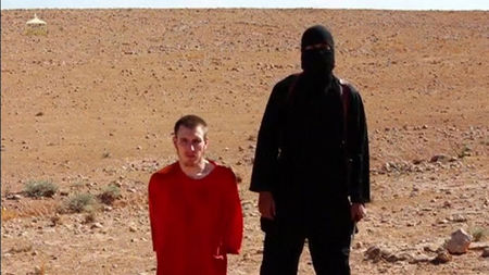 © Reuters. Still image from video shows a masked man standing next to a kneeling man identified as U.S. citizen Peter Edward Kassig