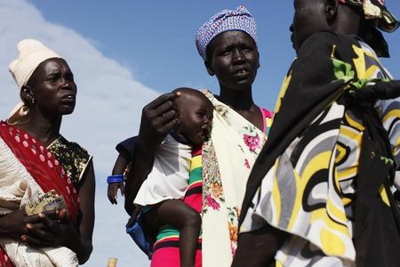 © Reuters. A woman carries a baby as she talks with other women talk at a food distribution in Minkaman