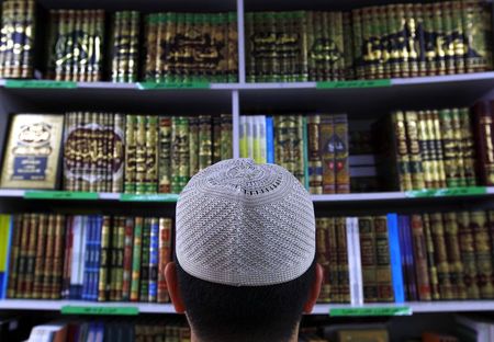 © Reuters. Man wearing an Islamic prayer cap, or "Kufi", looks at Islamic books on display at a bookshop located in the western Sydney suburb of Lakemba