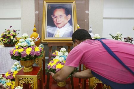 © Reuters. A man lays flowers as he prays for the health of Thailand's revered King Bhumibol Adulyadej at the Siriraj hospital in Bangkok