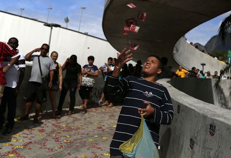 © Reuters. Menino joga panfletos enquanto moradores da Rocinha esperam para votar