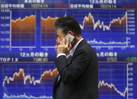 © Reuters. Men walk past an electronic board showing Japan's Nikkei average, outside a brokerage in Tokyo