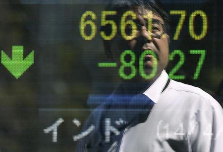 © Reuters. A man is reflected on an electronic board displaying a share price indicator outside a brokerage in Tokyo