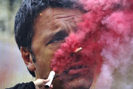 © Reuters. Manifestante coloca sinalizador em frente a cartaz com foto de premiê italiano Renzi em Milão