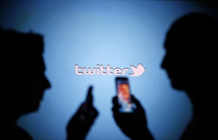 © Reuters. Men are silhouetted against a video screen with a Twitter logo as they pose with Samsung S3 and S4 smartphones in this photo illustration taken in the central Bosnian town of Zenica