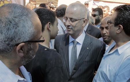 © Reuters. Palestinian Prime Minister Hamdallah speaks with Tariq Khdeir in a mourners tent at the home of Mohammed Abu Khudeir in Shuafat, Jerusalem