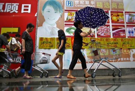 © Reuters. Local residents walk out of a supermarket in downtown Shanghai