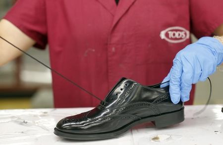 © Reuters. An employee works to set a shoe lace at the Italian luxury shoemaker Tod's in Sant'Elpidio a Mare