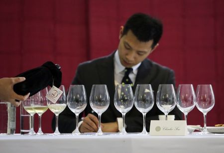 © Reuters. Waiter pours a selected Ningxia wine into a glass for a judge at a tasting event in Beijing