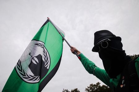 © Reuters. Man holds a flag of Anonymous hacker group during protest calling for protection of digital data privacy in Berlin