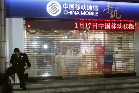 © Reuters. A security guard uses mobile phone in front of China Mobile store in Guangzhou