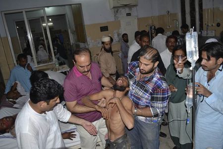 © Reuters. Apoioador de Imran Khan é ajudado por homens em hospital após se ferir em confusão durante protesto em Multan