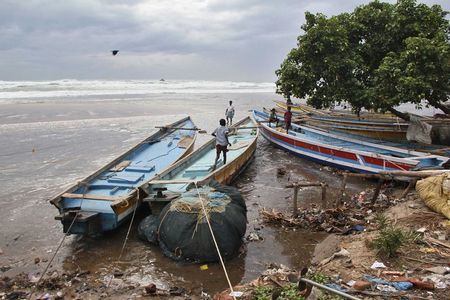 © Reuters. Boys walk on fishing boats by the shore before being evacuated, at Visakhapatnam district