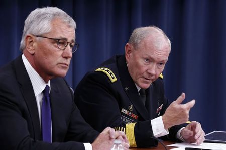 © Reuters. U.S. Secretary of Defense Chuck Hagel listens as Chairman of the Joint Chiefs of Staff Gen. Martin Dempsey speaks in a press briefing at the Pentagon in Washington