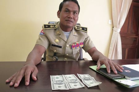© Reuters. Battambang police chief Brigadier General Sar Theth poses with notes from a seized haul of $7.16 million in counterfeit hundred-dollar bills, in Battambang