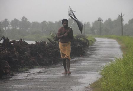 © Reuters. A man struggles with an umbrella in strong winds and rain caused by Cyclone Hudhud in Gopalpur in Ganjam district