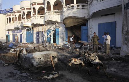 © Reuters. Soldiers and civilians inspect the aftermath of an explosion Sunday night outside the Oromo restaurant in Mogadishu