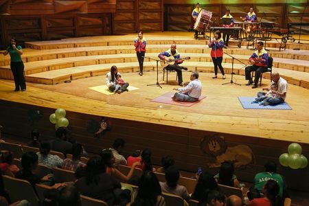 © Reuters. Parents and their children attend an interactive concert as part of the "New Members" program in the headquarters of "El Sistema" in Caracas