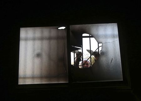 © Reuters. A Palestinian villager inspects a smashed window inside a mosque, that had been set alight, in the West Bank village of Aqraba