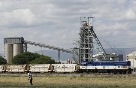 © Reuters. A man walks past a train carrying goods, at Anglo Platinum's Khomanani shaft 1 mine in Rustenburg