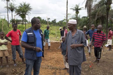 © Reuters. Kamara from WHO speaks with community leaders at the construction site of a Ebola Care Unit in Kamasondo Village