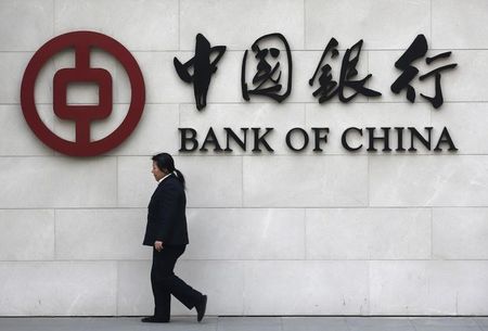 © Reuters. A woman walks past a sign of Bank of China at its branch in Beijing
