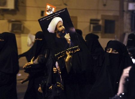 © Reuters. A protester holds up a picture of Sheikh Nimr during a rally in Qatif, against Sheikh Nimr's arrest