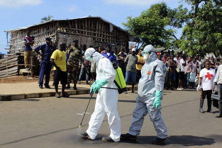 © Reuters. Profissionais de saúde usam spray desinfetante em suas roupas após remover corpo de mulher que morreu de Ebola em Freetown, em Serra Leoa