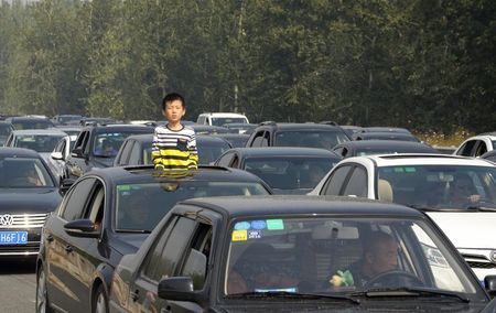 © Reuters. A boy looks out from the sunroof of a car during a traffic jam on the Jingshi Highway, on national day holidays in Zhuozhou