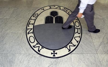 © Reuters. uMan walks on a logo of the Monte Dei Paschi Di Siena bank in Rome